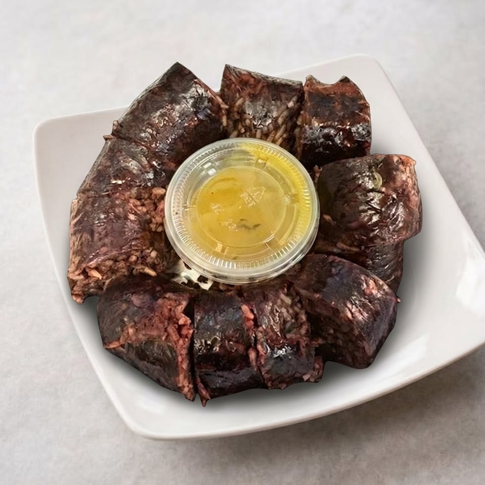Sliced Korean blood sausage (sundae) with a small container of yellow dipping sauce on a white plate.